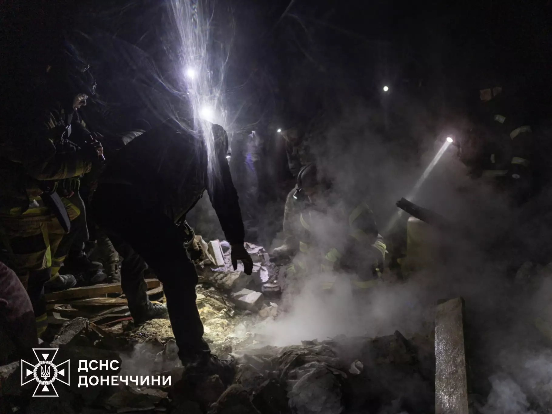 Рятувальники працюють вночі на місці руйнувань після обстрілів, використовуючи ліхтарі для пошуку постраждалих