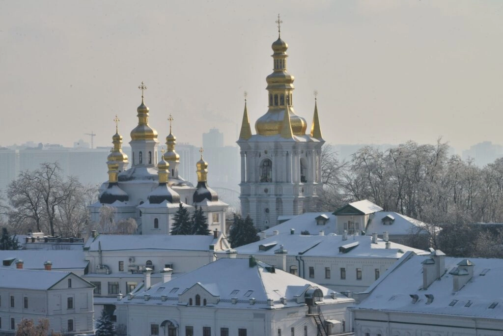 Києво-Печерська лавра взимку, засніжені куполи церков на тлі міського пейзажу Києва