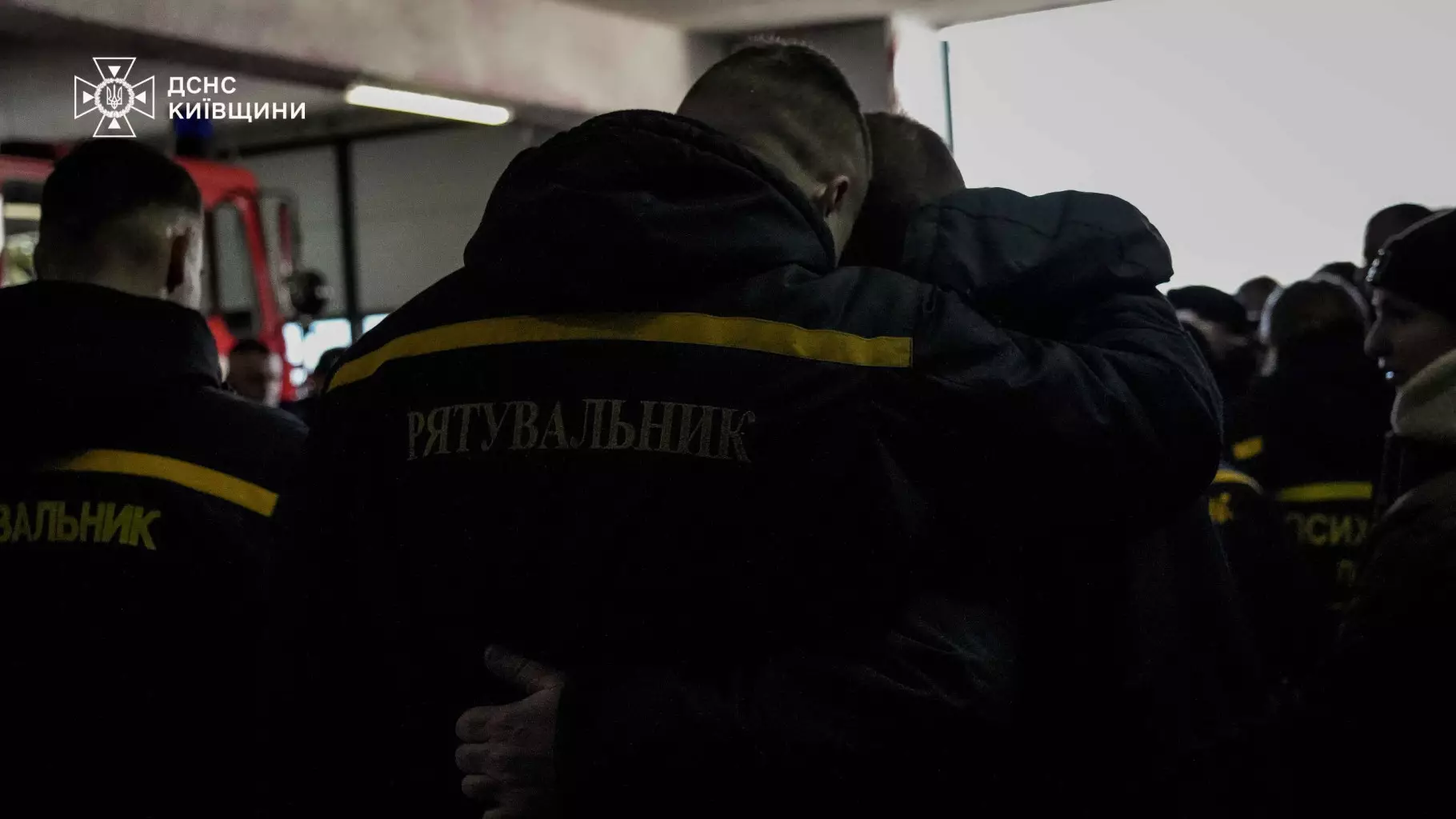 Рятувальники ДСНС України обіймаються під час прощання з колегою Михайлом Проценком у Київській області