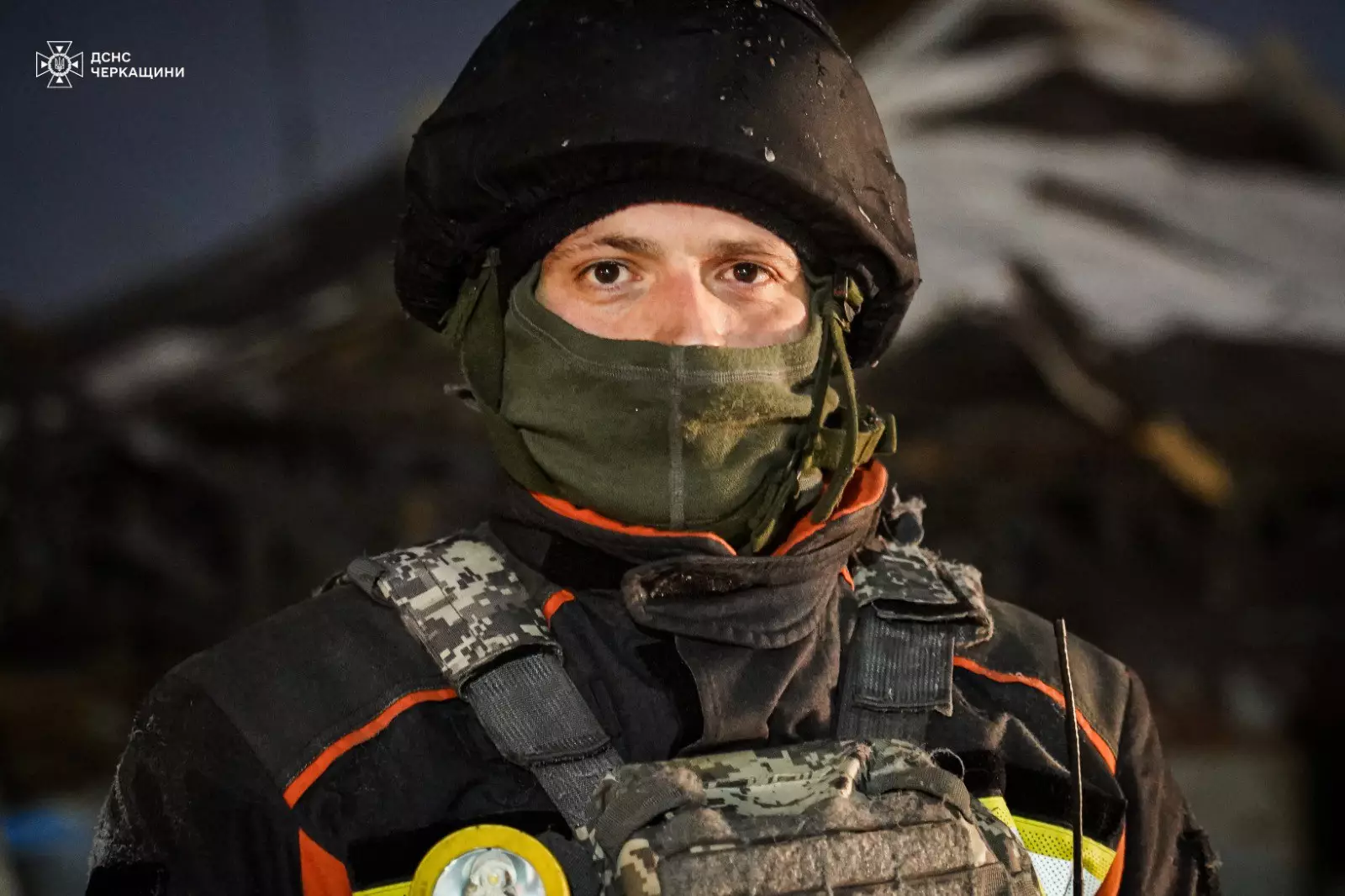 Рятувальник у захисному спорядженні на тлі зруйнованої будівлі після обстрілів Донеччини