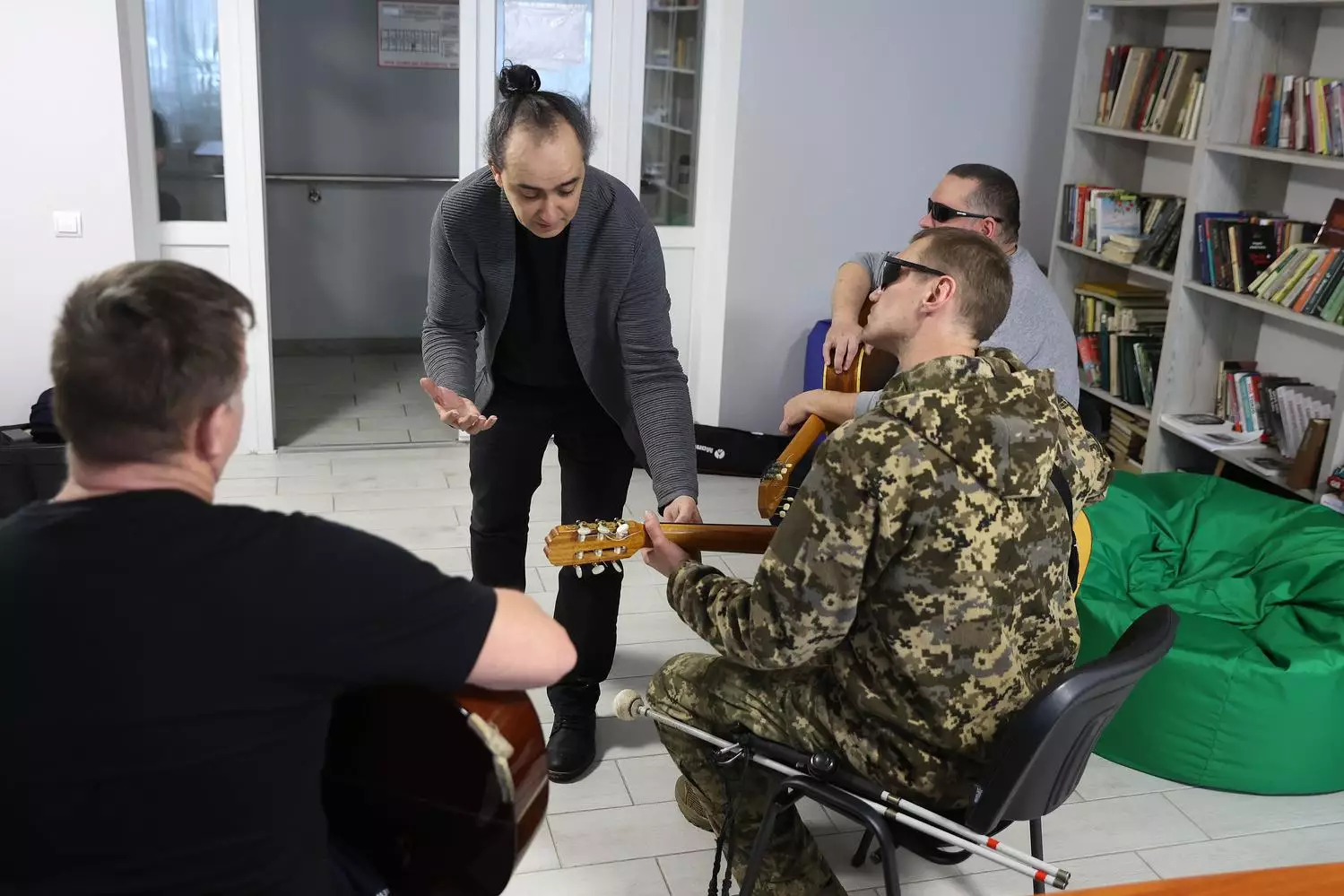 Ветерани в камуфляжі грають на гітарах у реабілітаційному центрі, отримуючи музичну терапію
