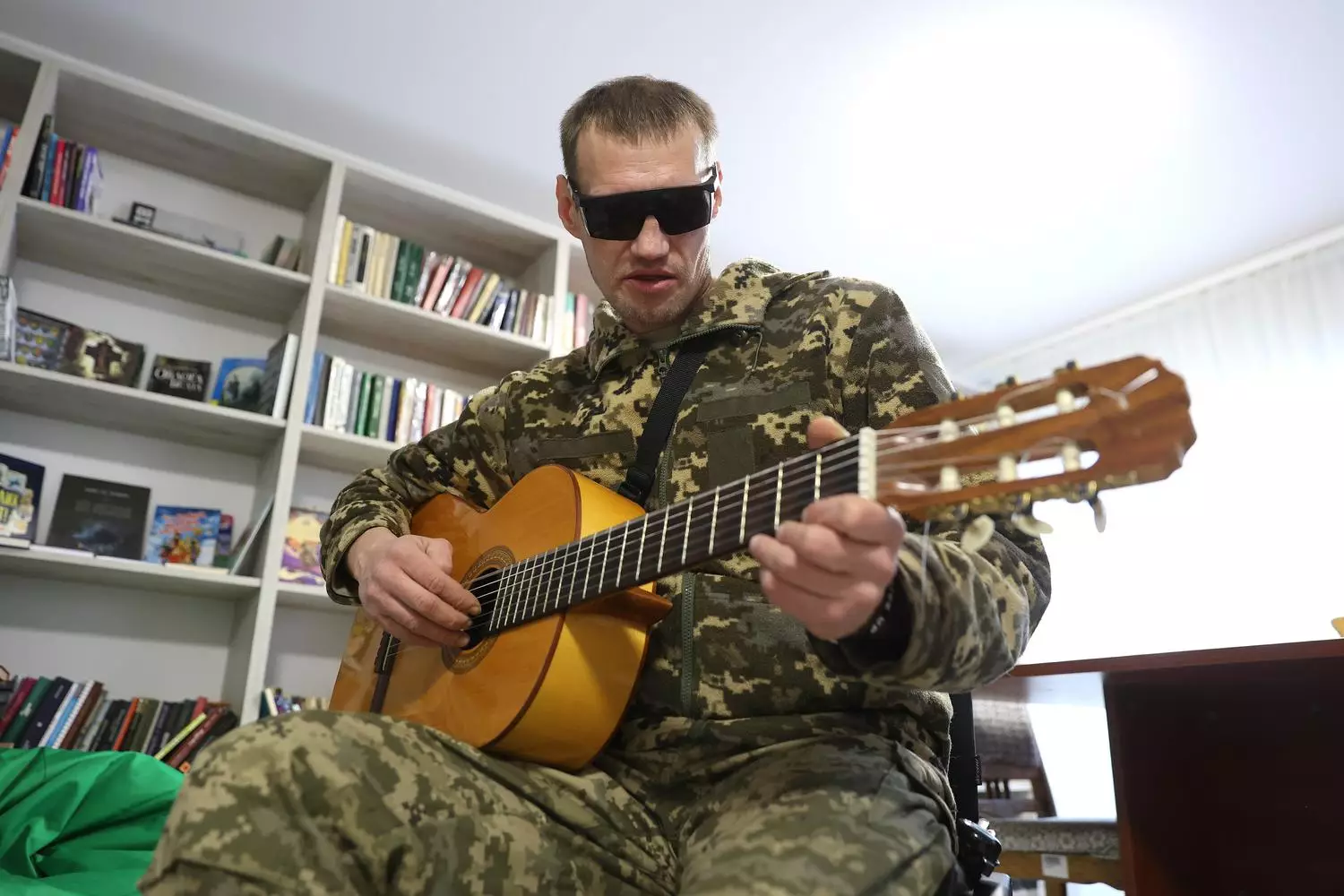 Ветеран у камуфляжі грає на гітарі в реабілітаційному центрі, підтримуючи емоційне відновлення