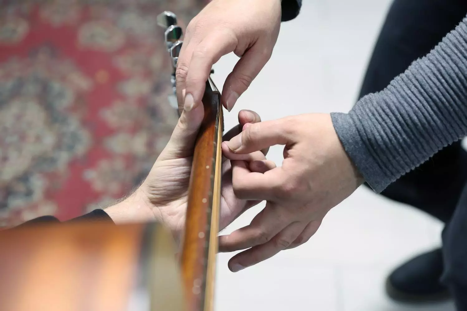 Дві пари рук тримають гітару, що символізує підтримку та навчання у реабілітації ветеранів