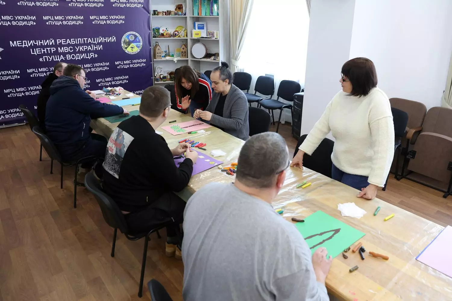 Люди в реабілітаційному центрі займаються арт-терапією, малюючи на папері за столом