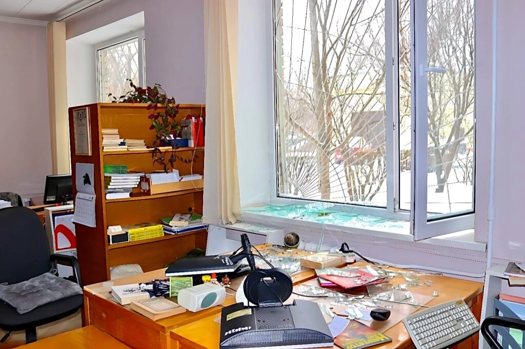 Пошкоджений кабінет бібліотеки: розбиті вікна, розкидані книги та офісне приладдя на столі