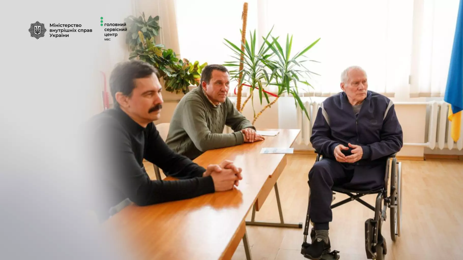 Троє чоловіків, один з них у візку, обговорюють безбар'єрність у сервісному центрі МВС