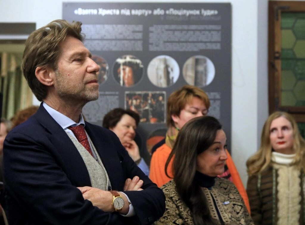 Чоловік у костюмі та жінки на виставці про реставрацію картини Караваджо в Софії Київській