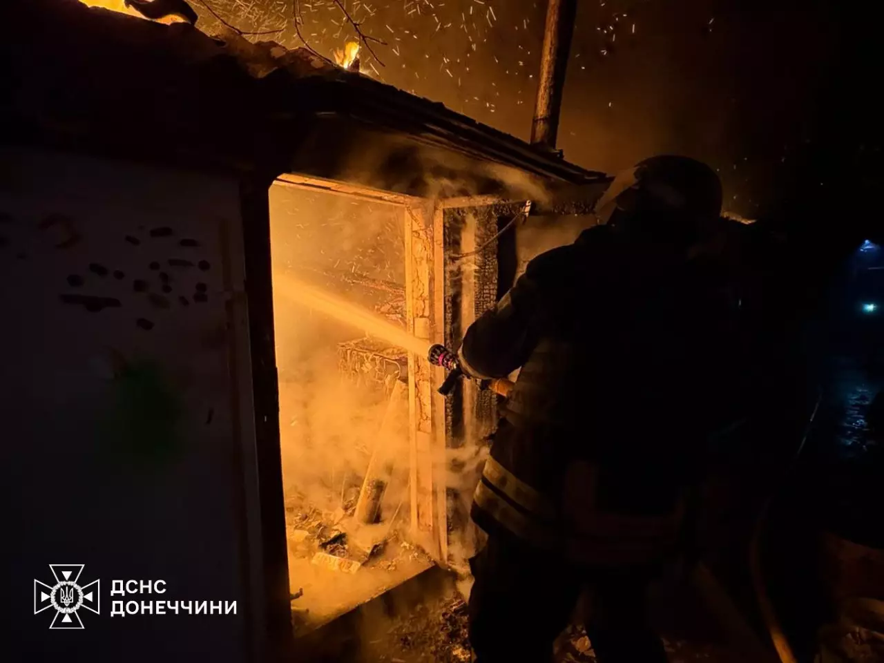 Пожежник гасить вогонь у будівлі, пошкодженій внаслідок обстрілів, вночі в Україні