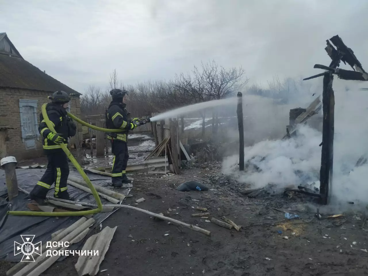 Рятувальники гасять пожежу на місці зруйнованої будівлі після обстрілу в Україні